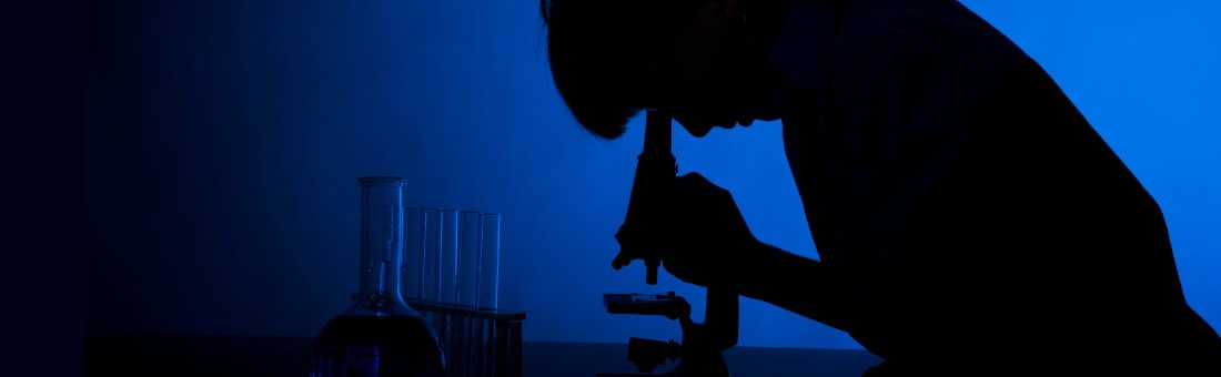 Researcher in a lab looking down a microscope